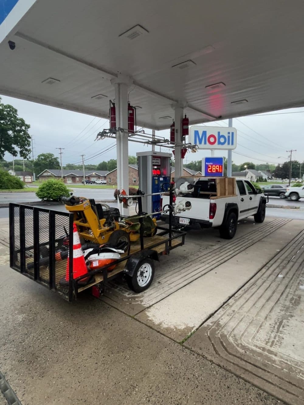 White truck at Mobil gas station with trailer and gas pump displaying $2.89 per gallon.