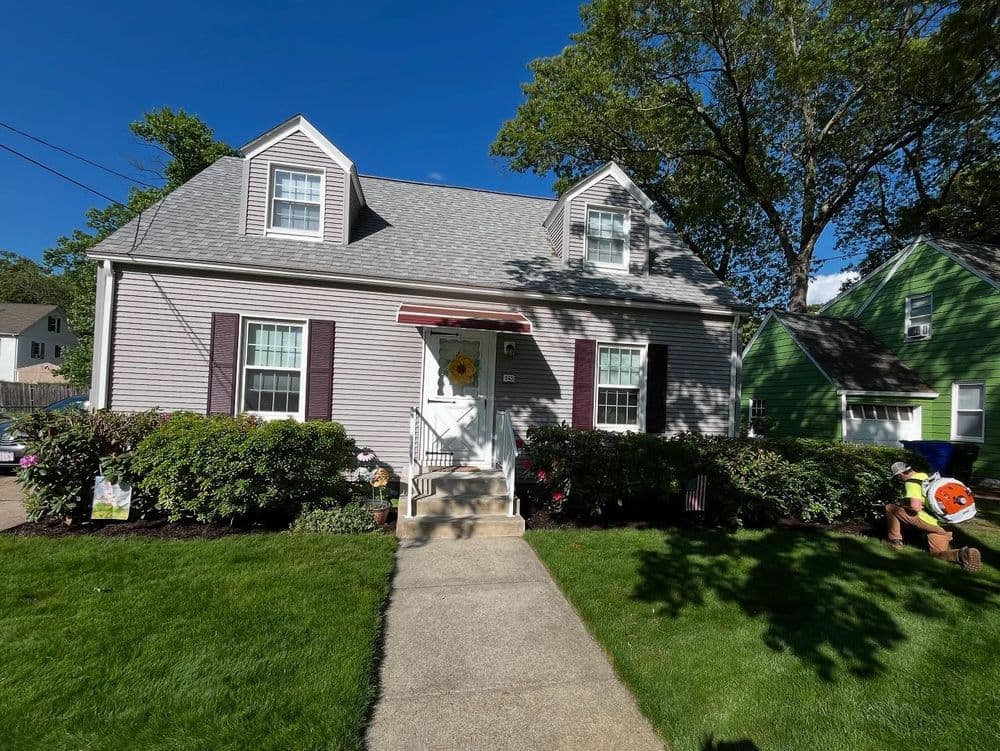 Charming two-story house with a landscaped front yard and sunny blue sky backdrop.